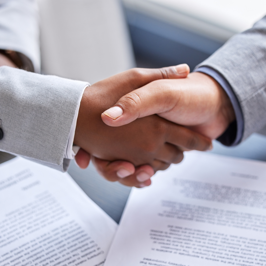 Two people shaking hands over legal documents, representing the trusted legal advice and strong local relationships built by Martin Shepherd Solicitors in North Finchley, Hertford and Potters Bar.