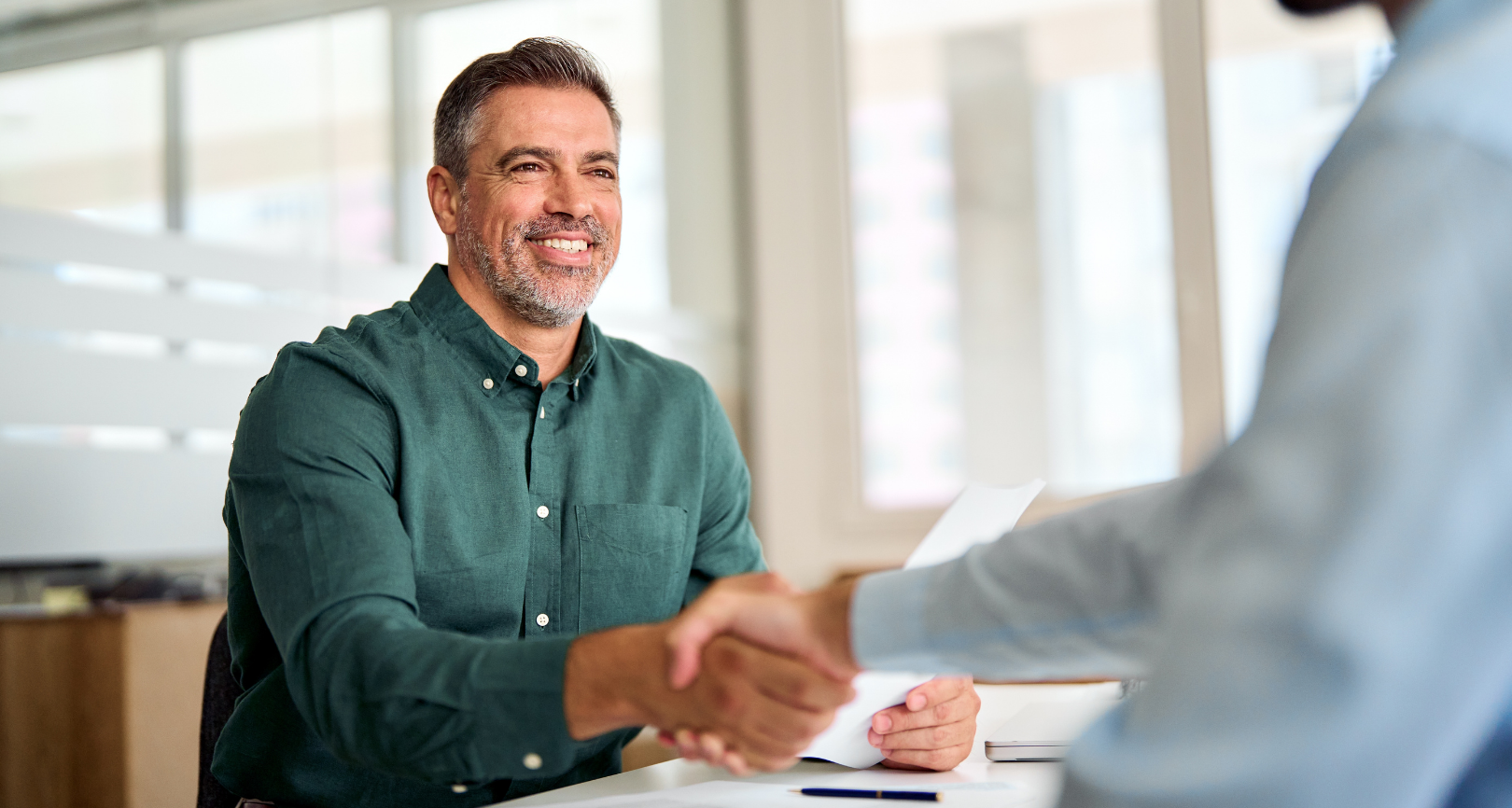 Man smiling and shaking hands during a meeting representing dispute resolution services by Martin Shepherd Solicitors in Potters Bar, Hertford and North Finchley.