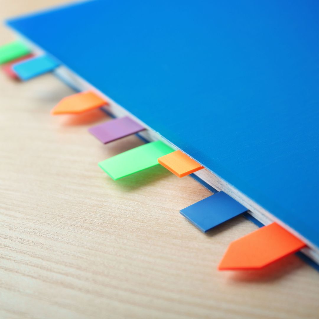 Colourful page tabs on a blue contract folder representing contractual dispute guidance by Martin Shepherd Solicitors in Potters Bar, Hertford and North Finchley.